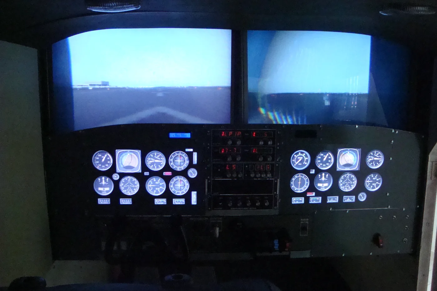 Cabina del simulador de vuelo con instrumentos encendidos y pantallas de visión exterior